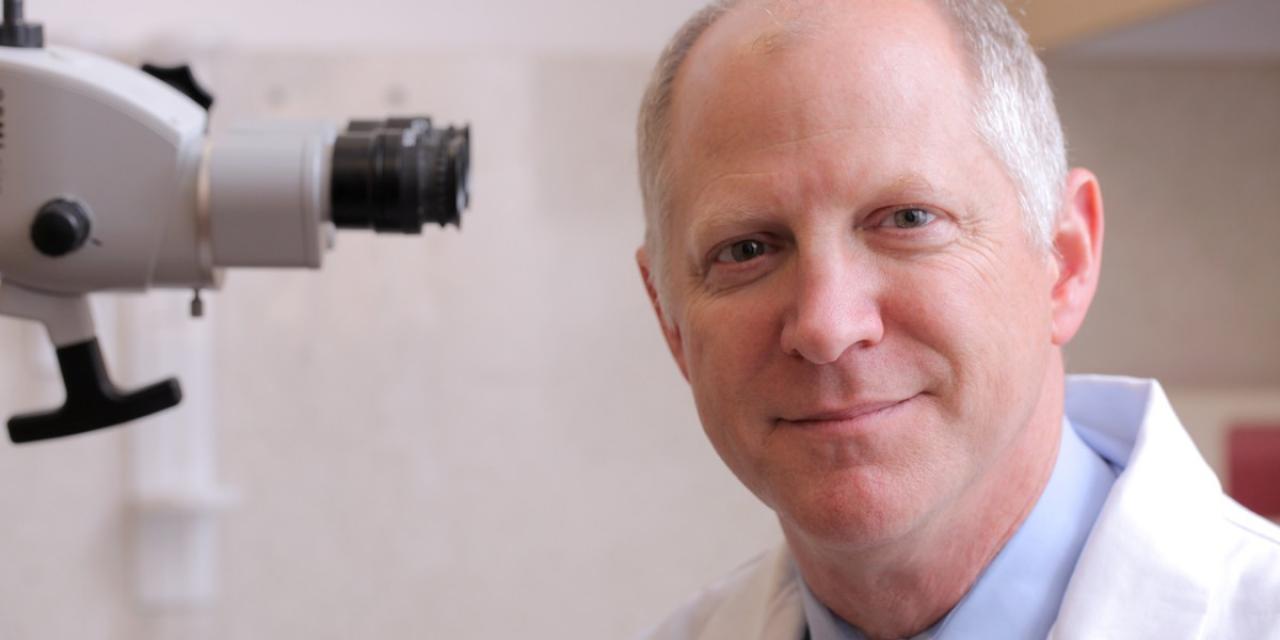 Dr. Lawrence Lustig in front of a microscope