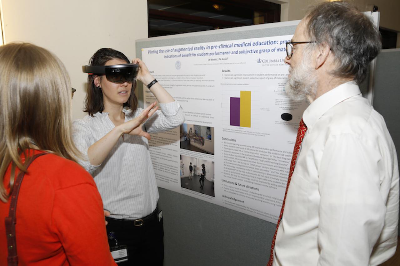 medical student talking with professors in front of her research poster