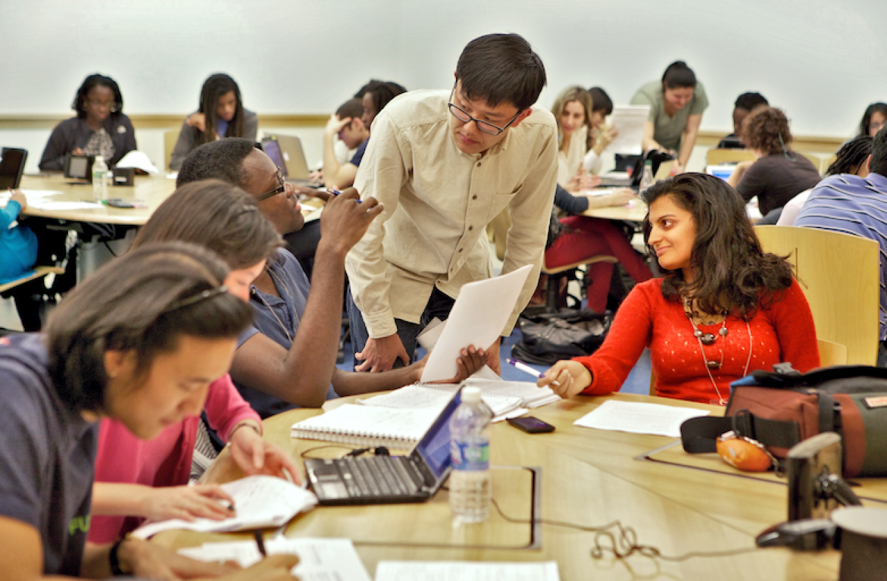 professor speaking with students seated at a table