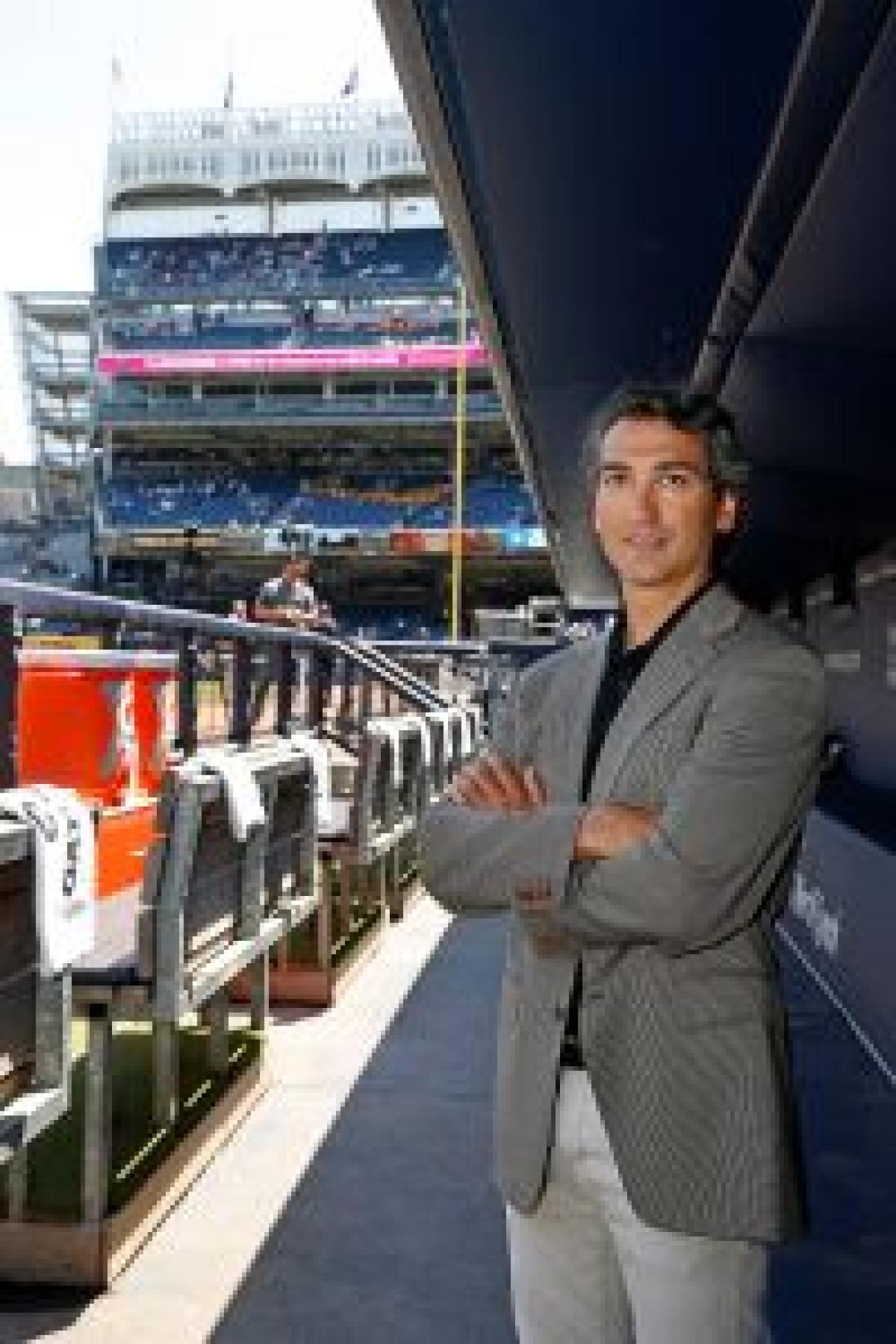 Dr. Christopher Ahmad standing in Yankees dugout with stadium seats view behind