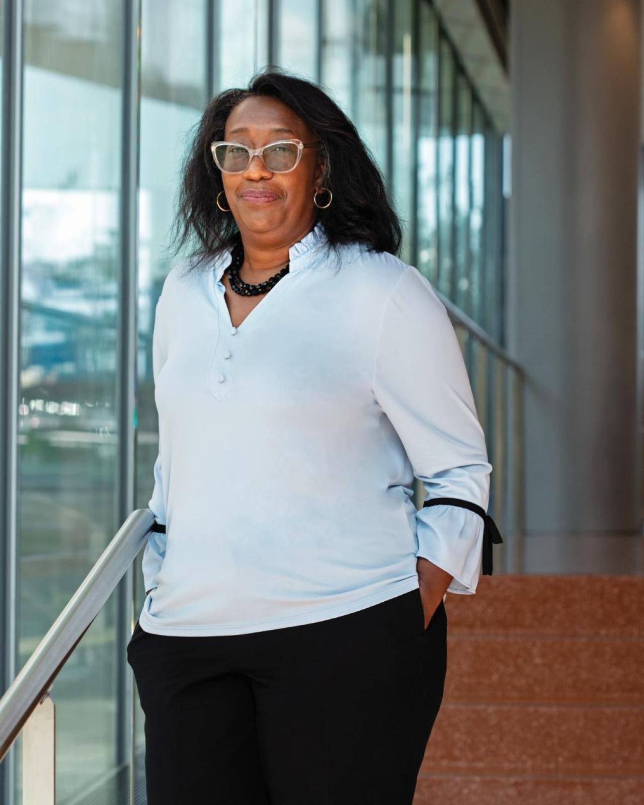 Monica L. Lypson poses on a staircase with her hands in her pockets