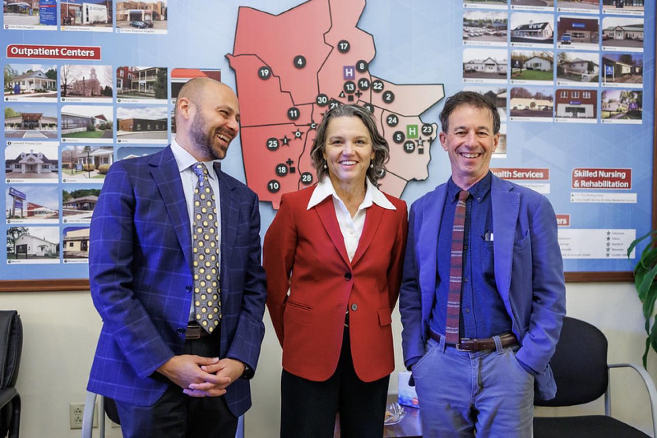 three people in suits smiling at the camera