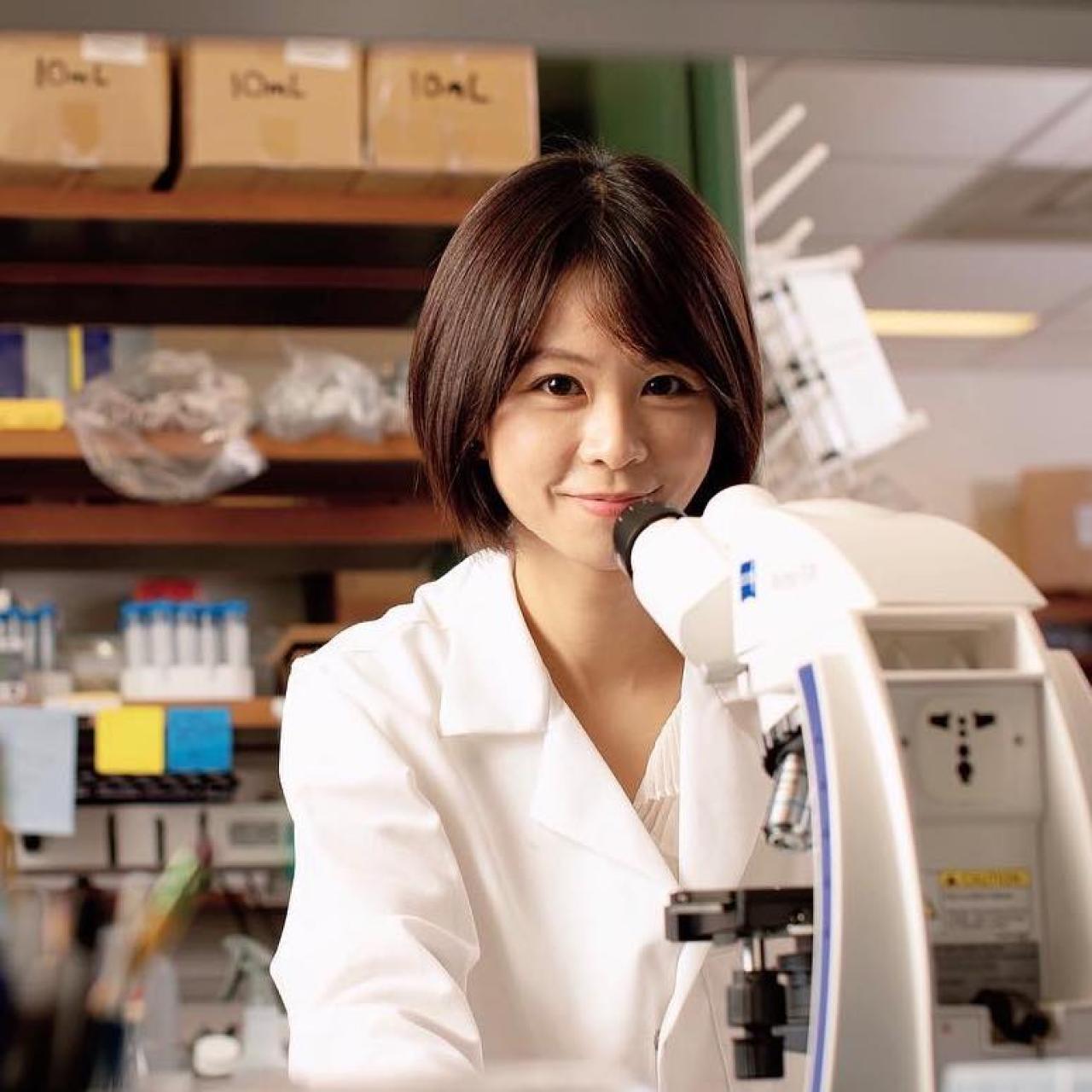 scientist sitting in front of a microscope