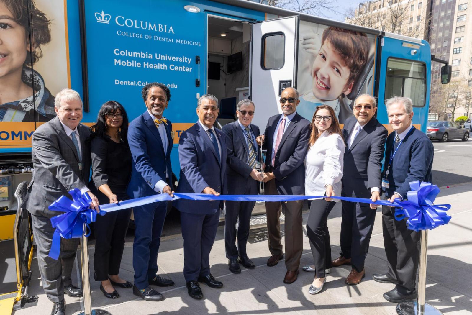 people standing in front of a mobile dental van