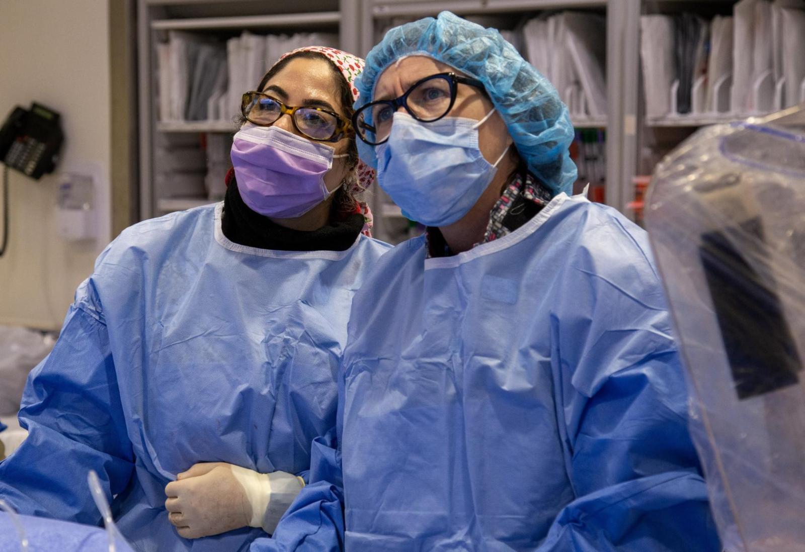 two doctors in surgical scrubs focus on patient in OR