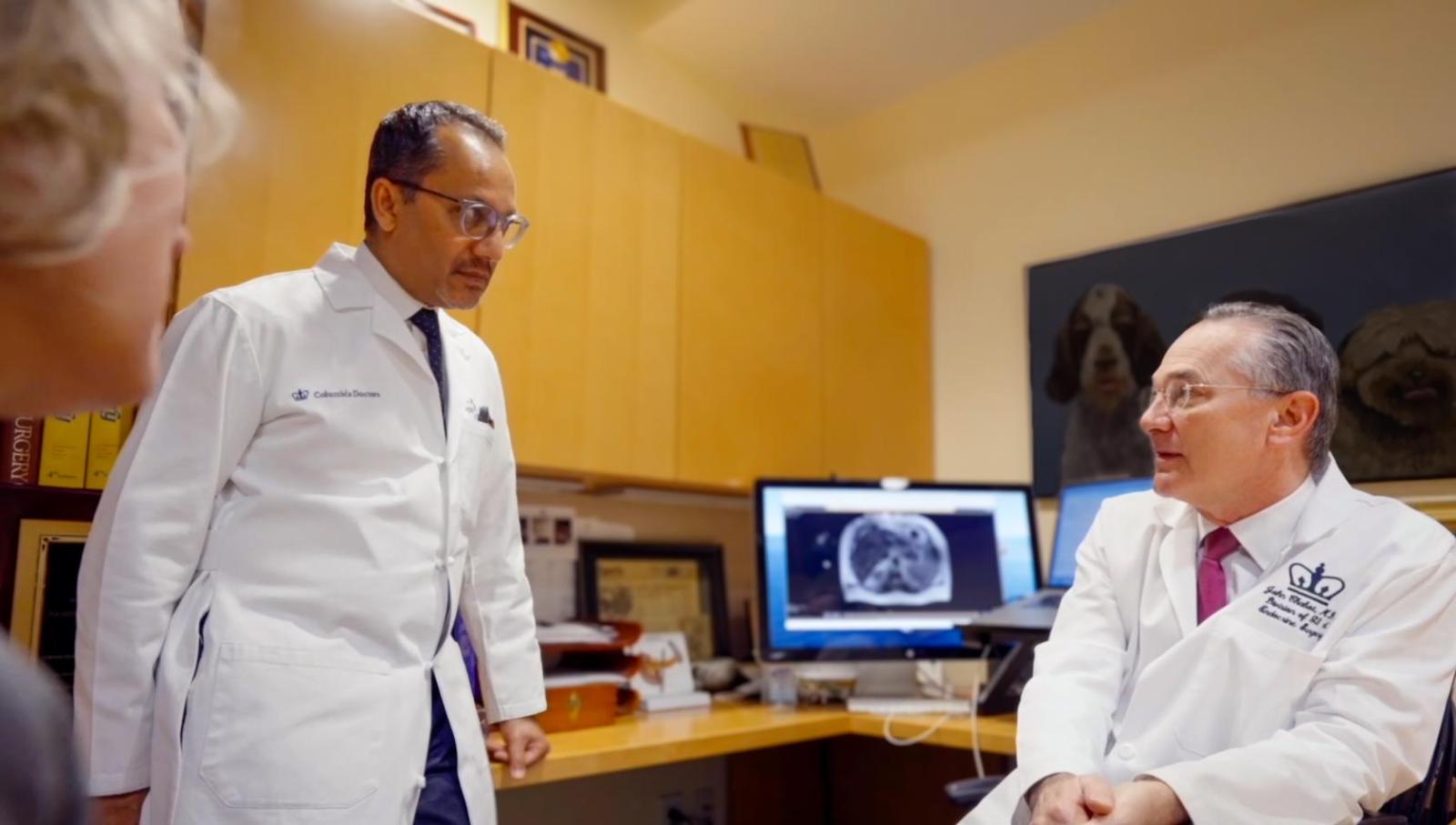 two doctors wearing white coats discuss a patient