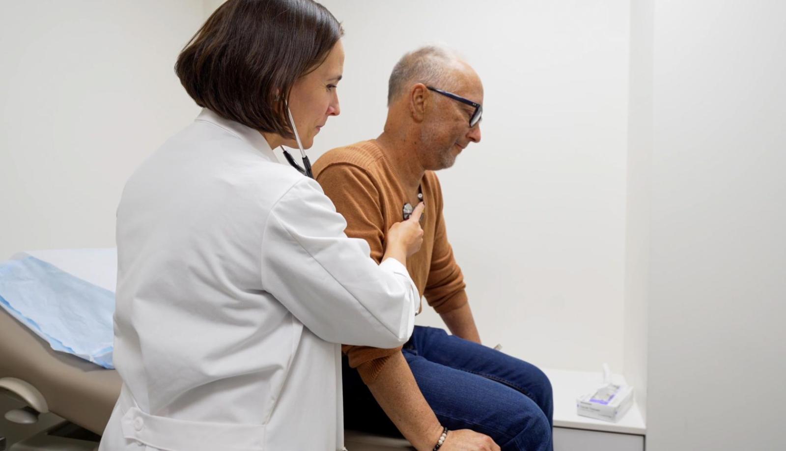 a doctor in a white coat applies a stethoscope to a patient's chest