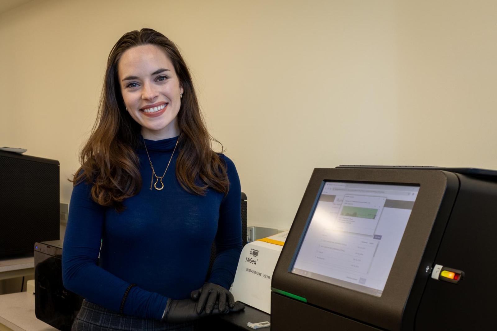 Deirdre Ricaurte standing next to a sequencing machine