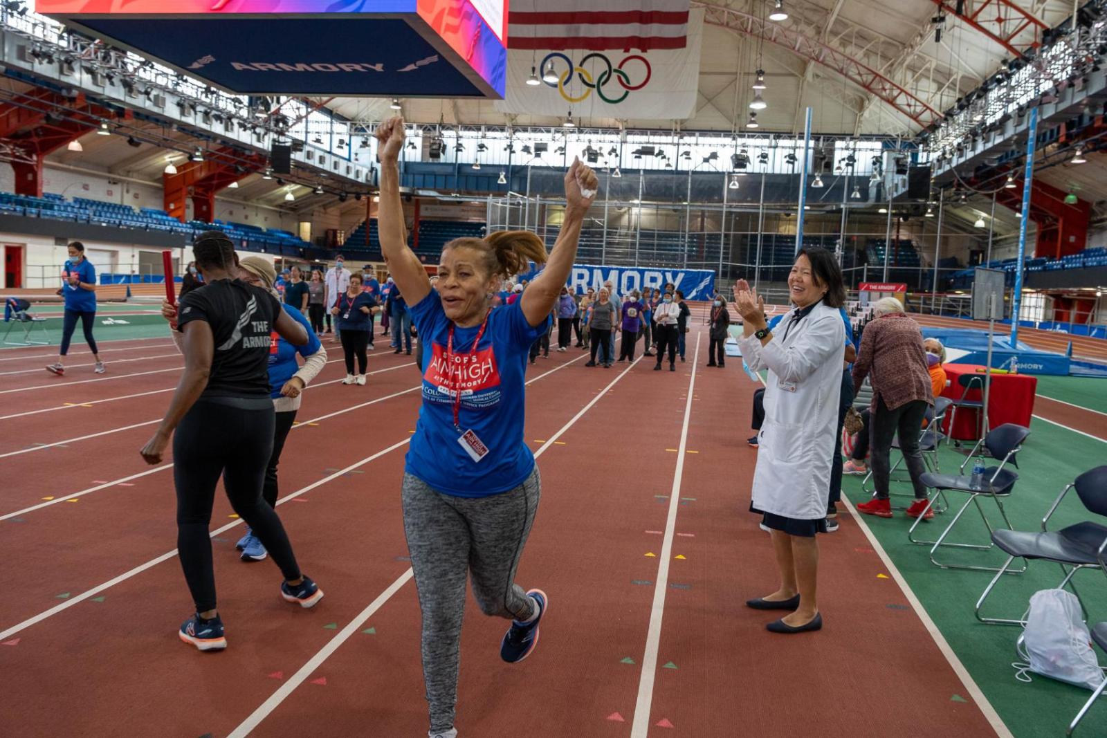 Woman runs on a track while a doctor cheers her on