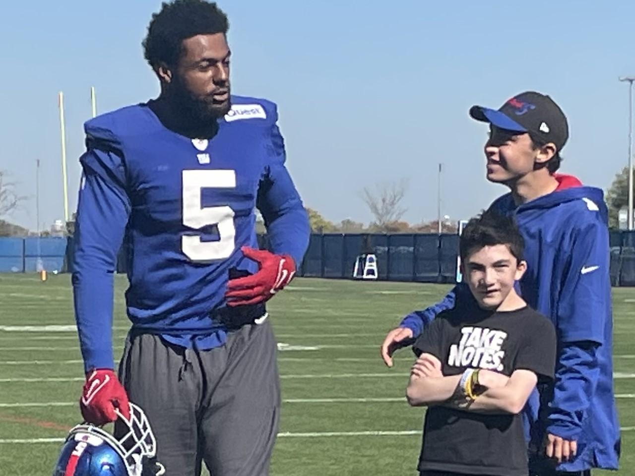 American football player standing next to two young fans
