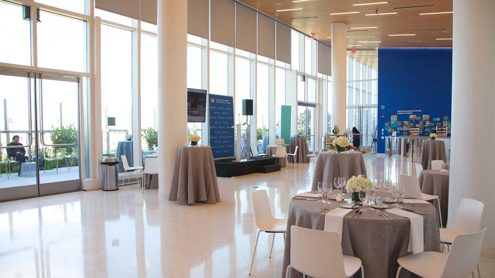 A bright event space with round dining tables set for a reception.