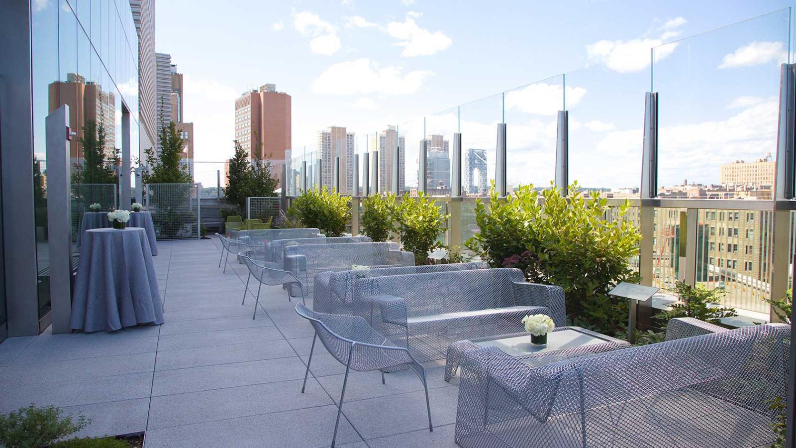 A rooftop terrace with seating and panoramic city views.
