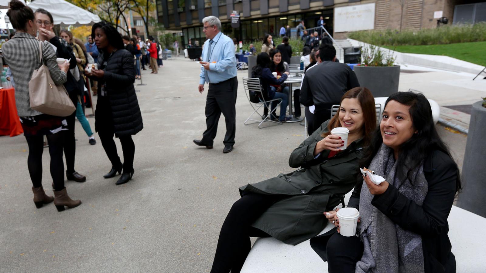 Two female Welcome Haven attendees sip apple cider and enjoy the medical center's outdoor plaza.