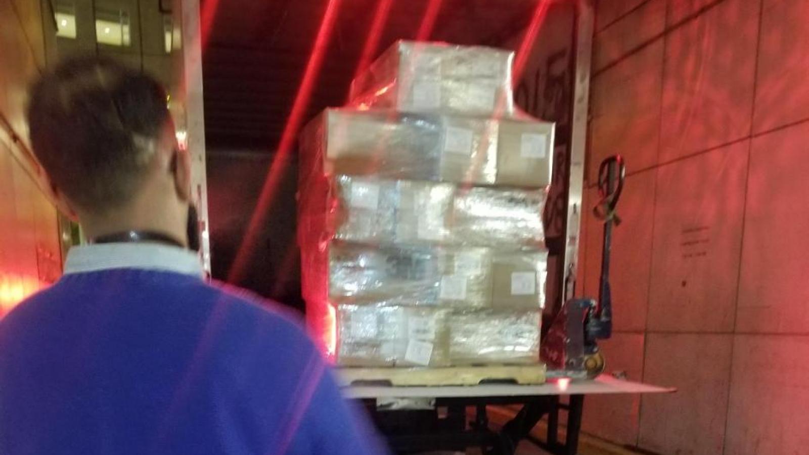 Man standing while truck unloads boxes.