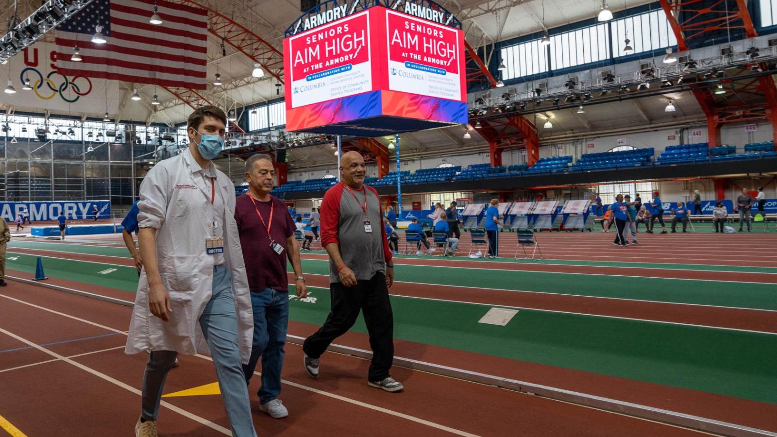 A doctor and two men walk around a track together.