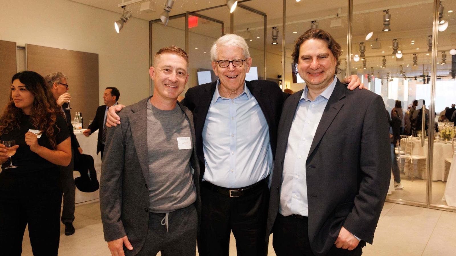 Three men stand together for a group photo