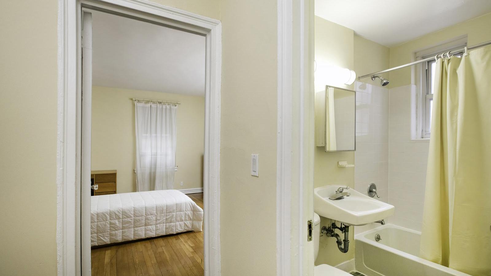 View of a sample bedroom and bathroom in a railroaded apartment in the Georgian Residence.