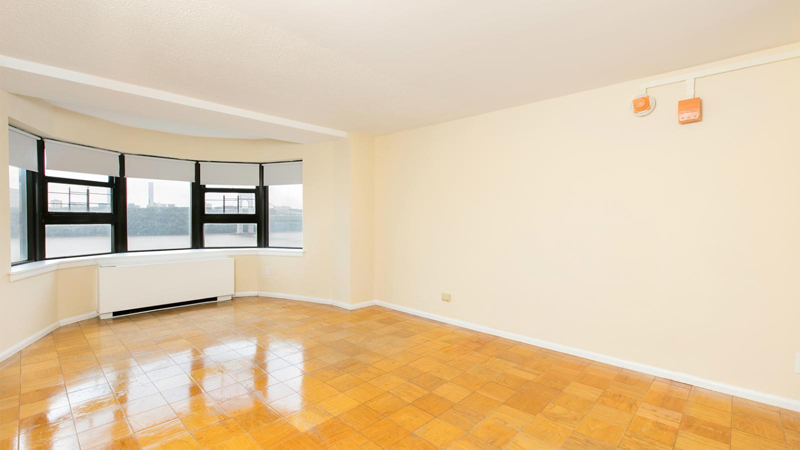 View of a sample unfurnished room in Tower 1, showing a bay-window view of the bridge.