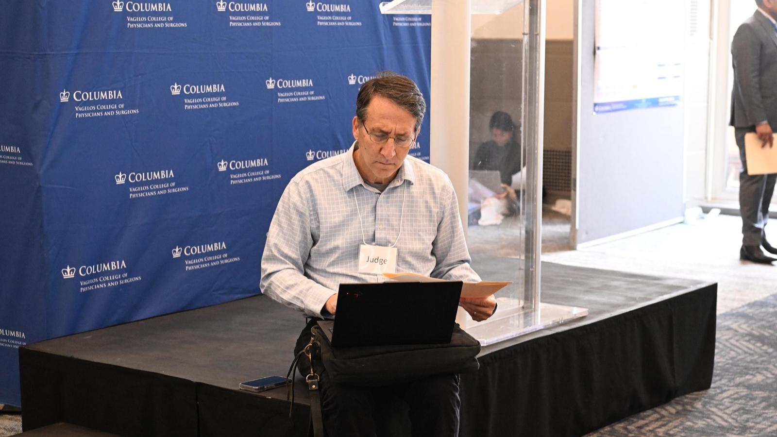 a single judge sitting on the podium enters his scores into a laptop