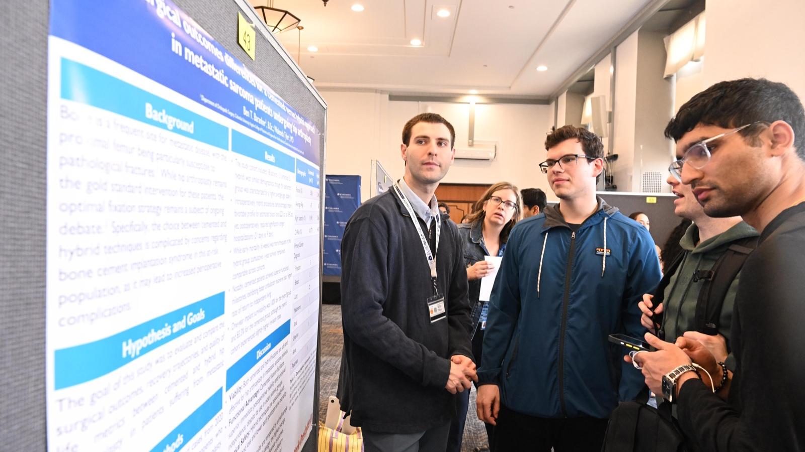 3 students reading a poster at student research day