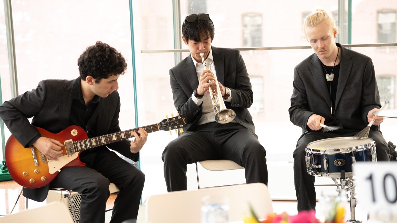 three jazz musicians playing guitar, trumpet and drums