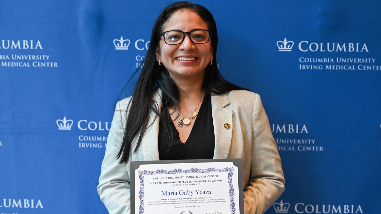 A CUIMC employee poses with her award