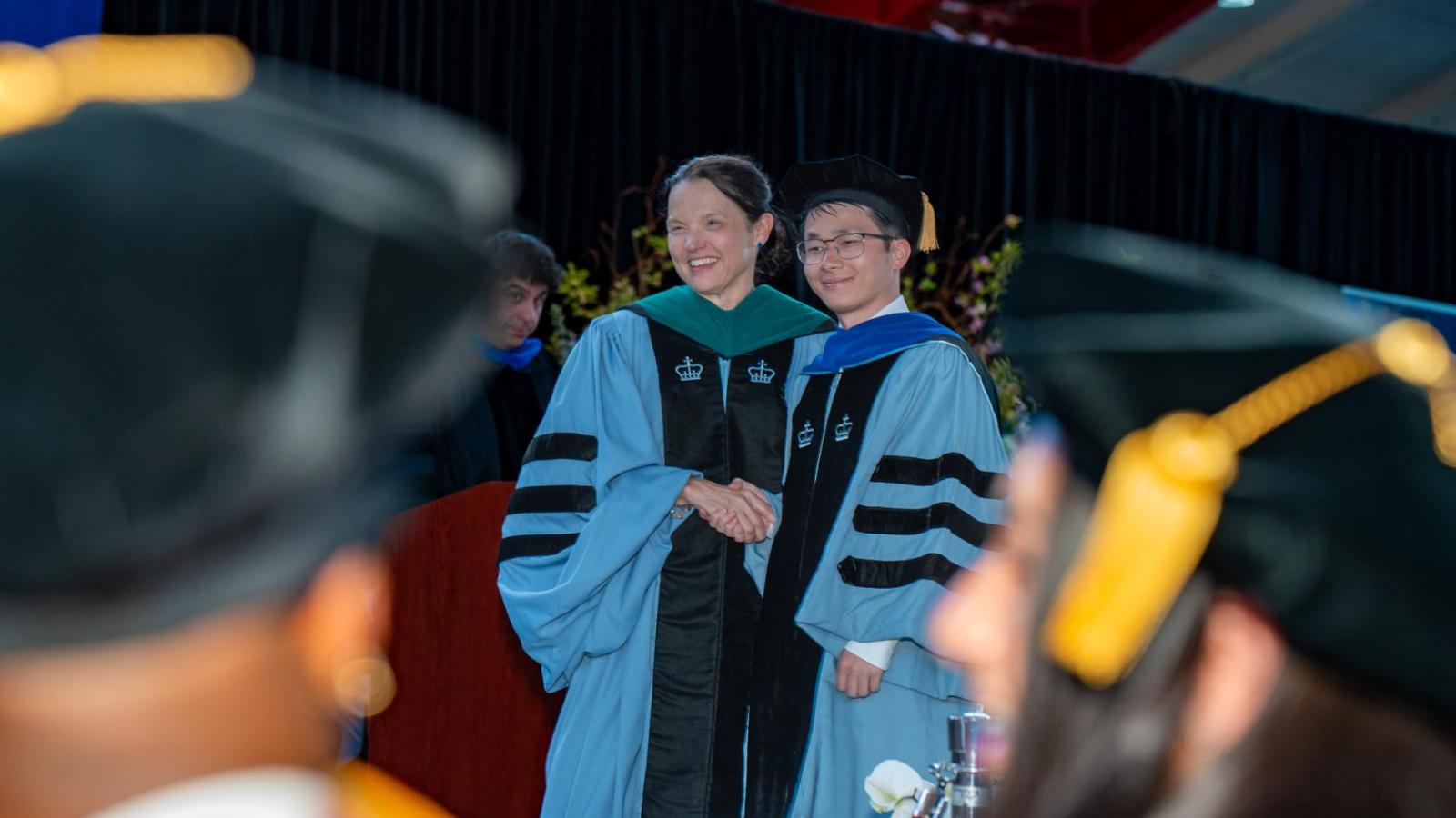 dean armstrong hands degree to a PhD graduate