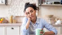 sleepy woman sitting at table with coffee and cookies