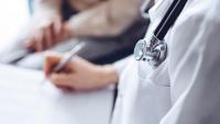 a health care provider writes notes in a patient chart