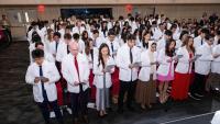 dozens of DDS students wearing white coats recite their oath