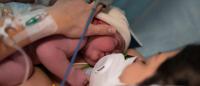 newborn and mother with mask on / Getty Images