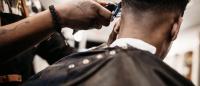 black barber trims hair of black customer