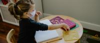 A child wearing a face mask works at a desk