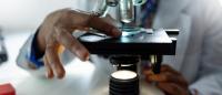 Black scientist looking through a microscope