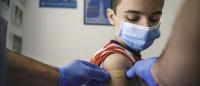 health care provider applies bandaid to arm of child who's just been vaccinated