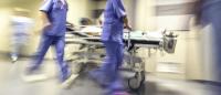 blurry image of patient on gurney being transported through hospital corridor