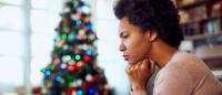 woman, looking stressed, sitting near Christmas tree