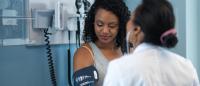 physician measuring blood pressure of a Black woman patient