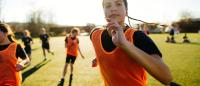 young woman playing soccer outside with her teammates
