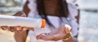 Black woman holding a bottle of sunscreen