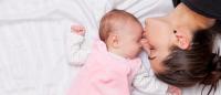 infant and mother lying on top of bed