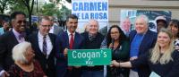 People gather around a sign that says "Coogan's Way"