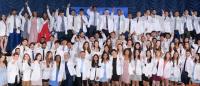 group photo of about 100 dental students wearing white coats