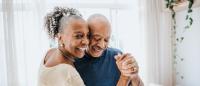 Senior couple dancing together in living room