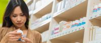 Dark haired woman looking at a supplements bottle in store