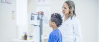 a boy has his weight and height measured by a pediatrician
