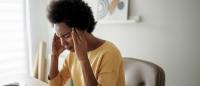 woman hands over temples having headache at office desk