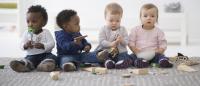 four babies sitting on the floor and playing with toys