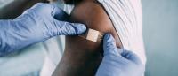 doctor putting bandaid onto arm after vaccination