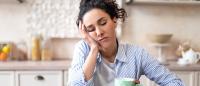 sleepy woman sitting at table with coffee and cookies